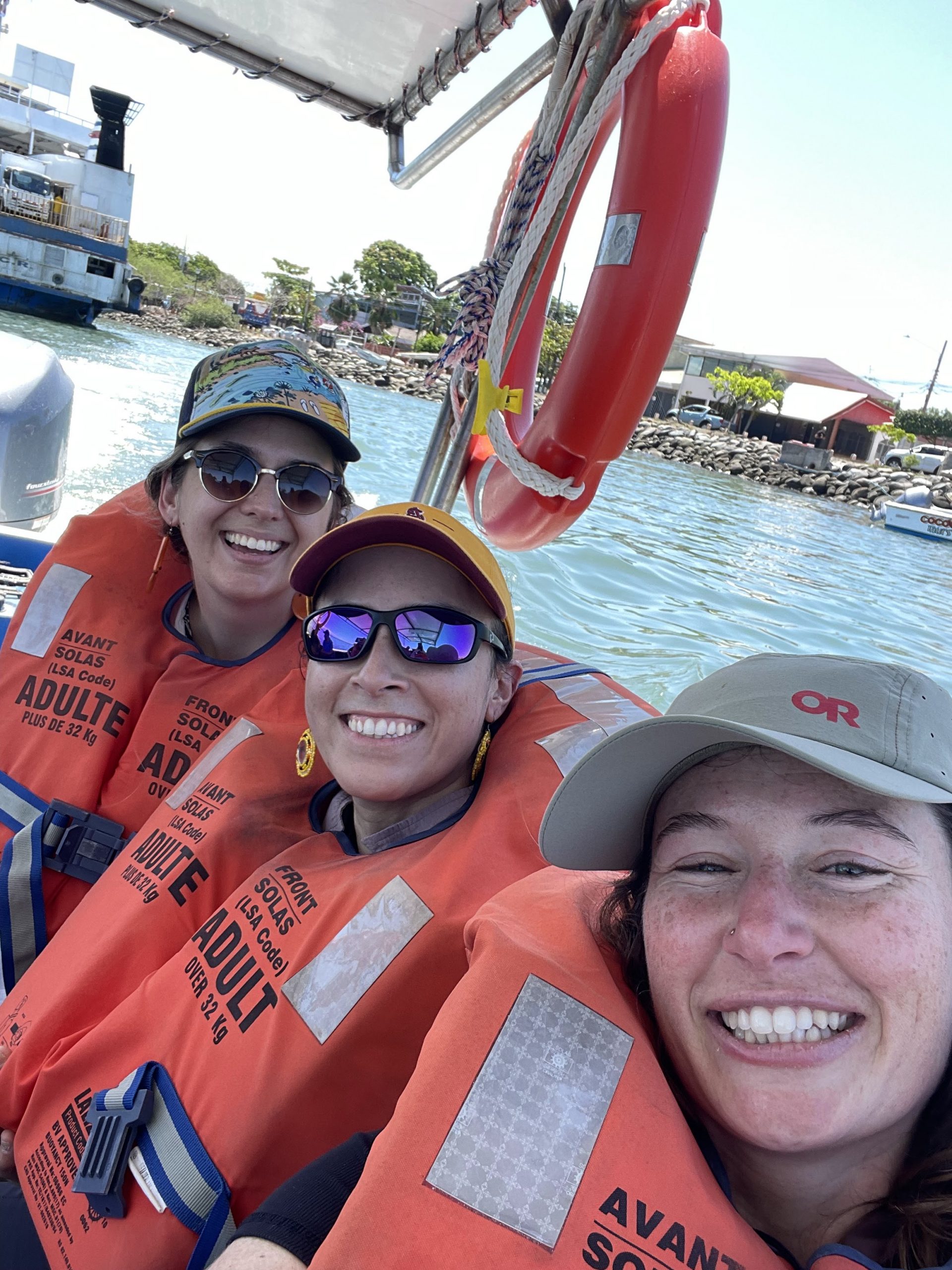 Three people on a boat wearing life vests