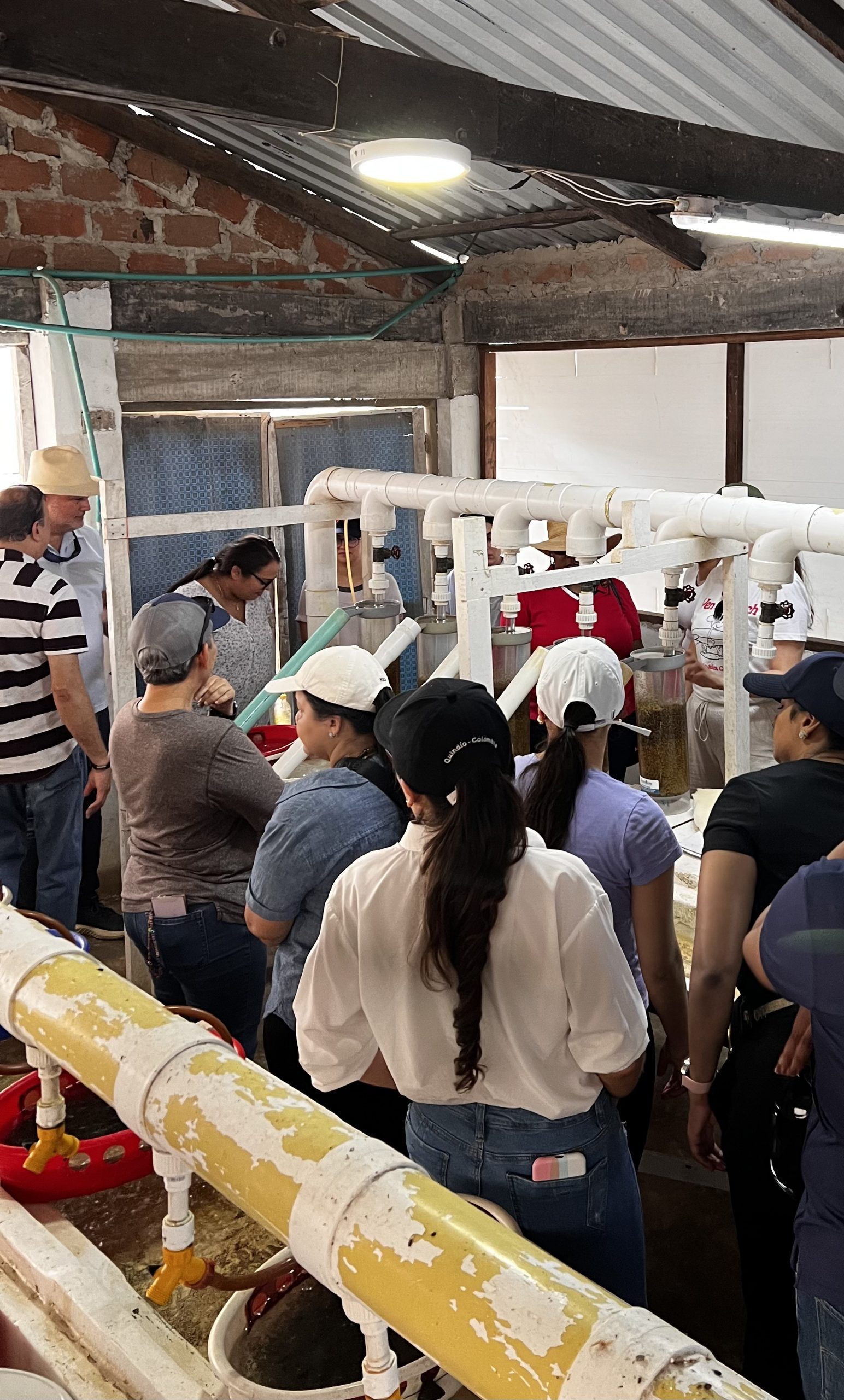 The PriceSmart group stands in a building with PVC pipes and aquatic systems.